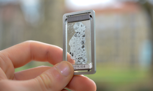 Hand holding a thin rock sample slice up to the light