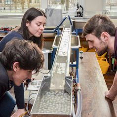 Three people observing a water-flow experiment