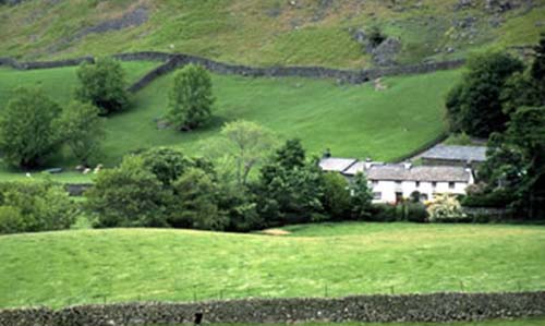 A white house nestled among rolling, green hills.