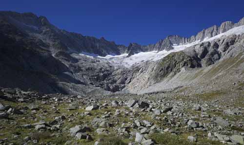 A wide-angle shot of a valley carved out by glaciers with snow-capped mountains in the background.