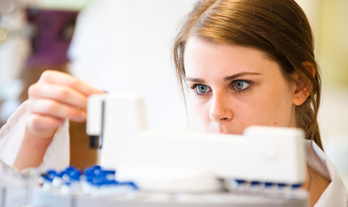 Female scientist loading a test tube into a centrifuge