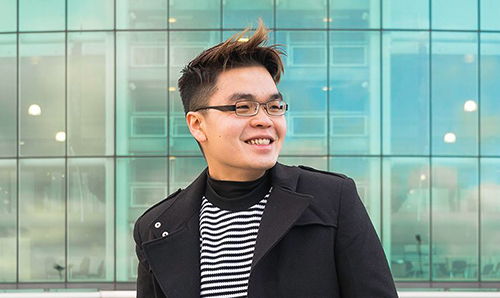 Male student smiling in front of Old Trafford's exterior