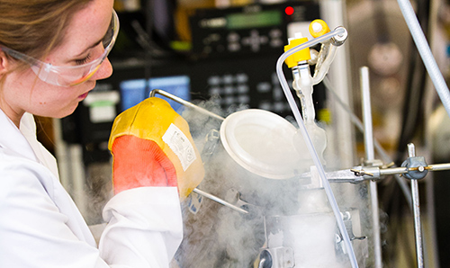 A female researcher pouring out a steam-filled container