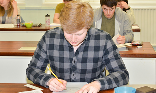 A male student writing at his desk