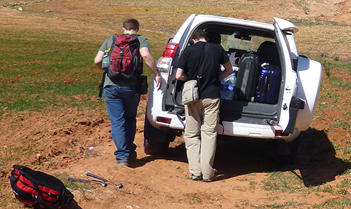 Two researchers taking kit out of their van in a field in Morocco